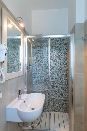 a bathroom with a sink and a glass shower at Hotel Smart Cervia B&B in Cervia