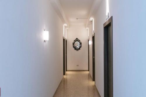 a hallway with white walls and a clock on the wall at Hotel Smart Cervia B&B in Cervia