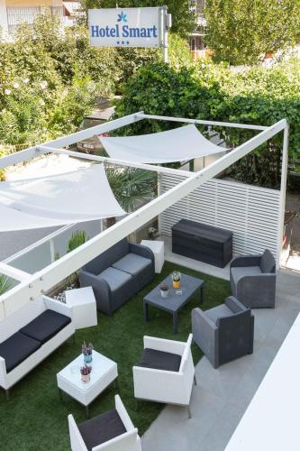 a patio with couches and tables on the grass at Hotel Smart Cervia B&B in Cervia
