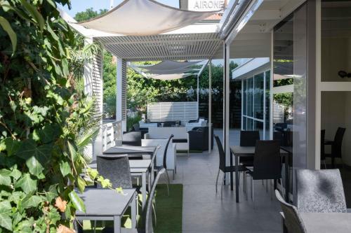 an outdoor patio with tables and chairs and plants at Hotel Smart Cervia B&B in Cervia