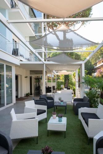a patio with white couches and tables on the grass at Hotel Smart Cervia B&B in Cervia