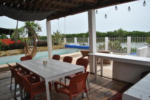 un patio con mesa, sillas y piscina en +221 Lagune Beach House, en Mbodiène