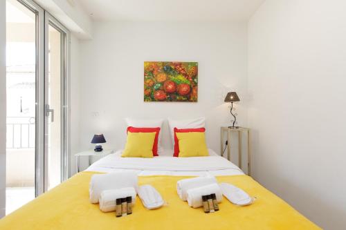 - une chambre blanche dotée d'un grand lit avec des oreillers jaunes et rouges dans l'établissement Greg YourHostHelper, à Cannes