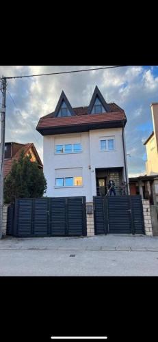 a white house with a fence in front of it at Urban Cozy Apartments Zagreb in Zagreb