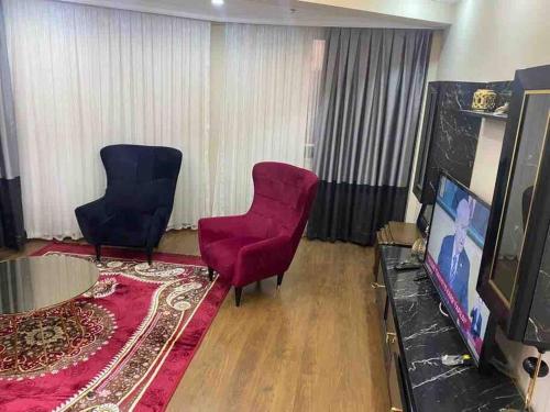 Duplex apartment next to airport في Arnavutköy: غرفة معيشة مع كرسيين حمر وتلفزيون