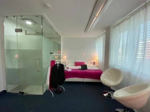 ein Bad mit einem rosa Bett und einer Glasdusche in der Unterkunft Business Hotel Wiesbaden PRIME in Wiesbaden