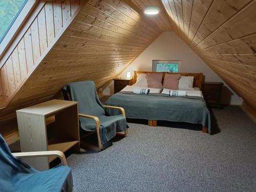 a bedroom with a bed and two chairs in a attic at Penzion Starovice in Starovice