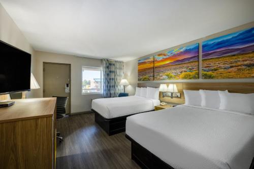 a hotel room with two beds and a flat screen tv at Days Inn by Wyndham Roswell in Roswell