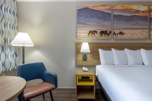 a hotel room with a bed and a desk and a chair at Days Inn by Wyndham Roswell in Roswell