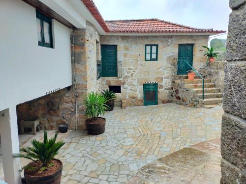 a stone house with potted plants in a courtyard at Quinta da Lage Agroturismo e Enoturismo in Celorico de Basto