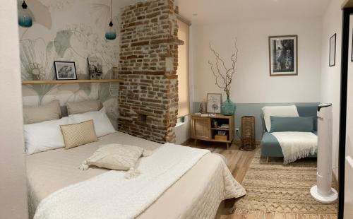 a bedroom with a white bed and a brick wall at LE SAINT CYP - Toulouse - appart entier cosy et au calme, proche du métro in Toulouse