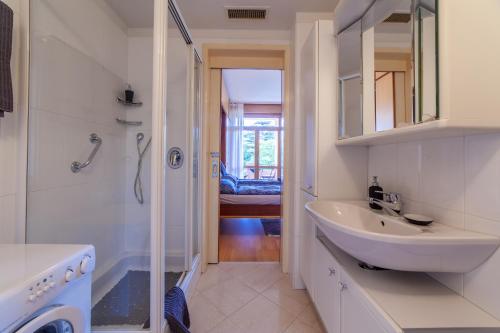 bagno bianco con lavandino e doccia di Appartamento Indaco Armonya a Merano