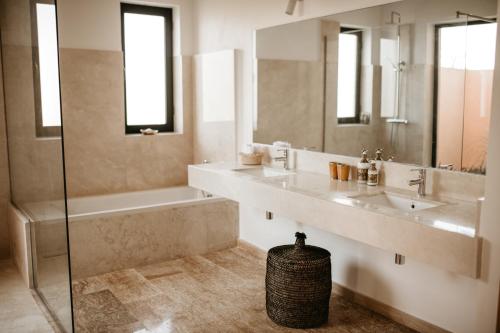 La salle de bains est pourvue de 2 lavabos, d'une baignoire et d'une douche. dans l'établissement Villa Aljana Marrakech, à Marrakech