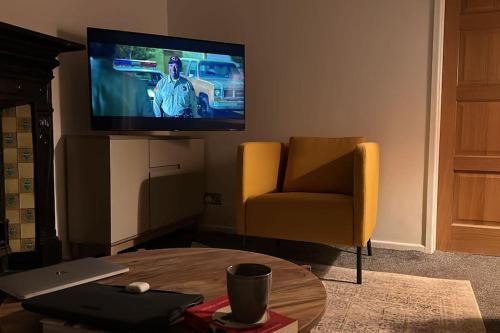 a living room with a tv and a chair and a table at Revamped Holywood town centre house in Holywood