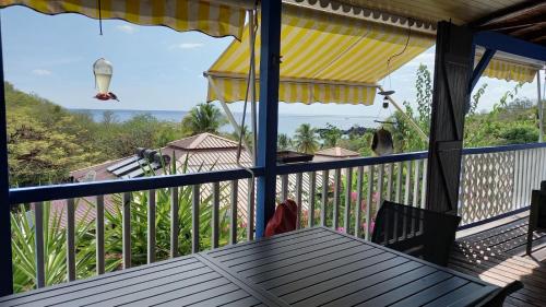a porch with a table and an umbrella on a balcony at Le Frégate ,belle vue mer , 150M de la plage, SPA privé in Bouillante
