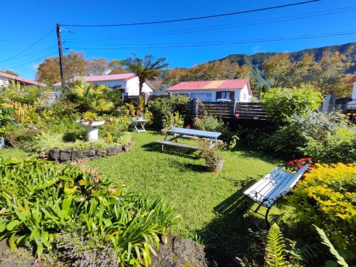 a garden with a bench and flowers and a house at Maison de charme, en Plaine Poésie -chez l'habitant- in La Plaine des Palmistes