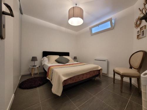 um quarto branco com uma cama e uma cadeira em Appartement Salbris- Parking Gratuit em Salbris