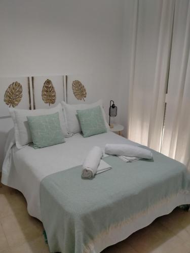 een witte slaapkamer met een wit bed met groene kussens bij Apartamento las tres lunas in Sanlúcar de Barrameda
