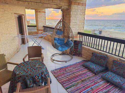a porch with a hammock and chairs and the beach at Hotel appartment sea view 3 bedrooms 3 toilets 4th floor Bellevue village agami alexandria families are preferred available all year days & 5 blankets available in Alexandria