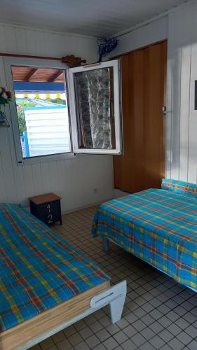 a room with two beds and a window at Le Frégate ,belle vue mer , 150M de la plage, SPA privé in Bouillante