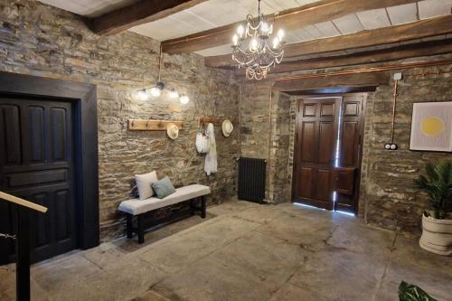 a room with a stone wall with a bench and a chandelier at La Escondida in Caboalles de Abajo