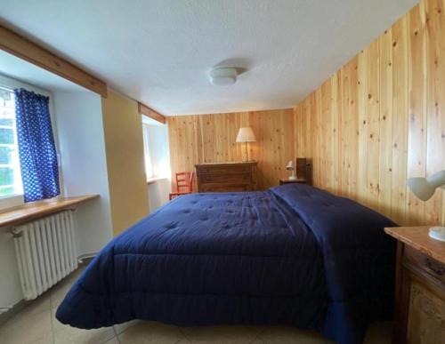 a bedroom with a blue bed in a room with wooden walls at APPARTAMENTO CON GIARDINO in Crépin