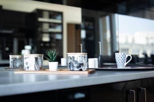 a counter with three cups and a plate with a plant at Martonfalvi Penthouse w Jacuzzi in Debrecen