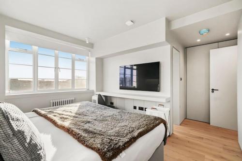 a bedroom with a bed and a flat screen tv at Luxury Kensington Flat with Terrace and AC in London