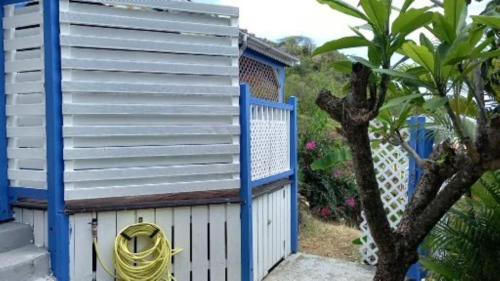 a blue fence with a yellow hose next to a house at Le Frégate ,belle vue mer , 150M de la plage, SPA privé in Bouillante