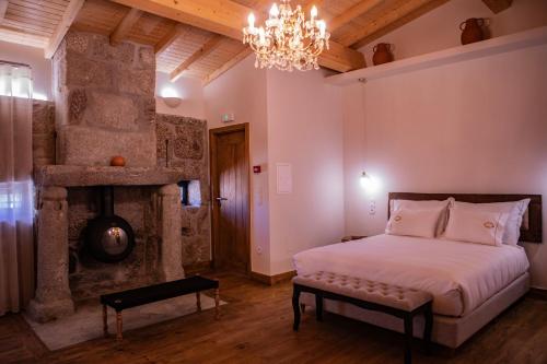 a bedroom with a bed and a fireplace and a chandelier at Quinta de São Francisco Houses in Viseu
