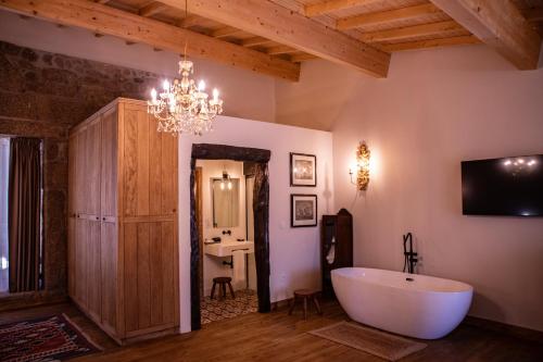 uma casa de banho com uma banheira, uma televisão e um lustre em Quinta de São Francisco Houses em Viseu