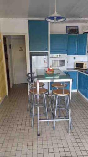 a kitchen with blue cabinets and a table and stools at Le Frégate ,belle vue mer , 150M de la plage, SPA privé in Bouillante