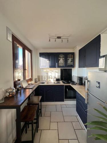 a kitchen with blue cabinets and a table and a refrigerator at Superbe appartement proche Paris 30 min RER in Saint-Maur-des-Fossés