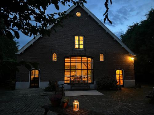a large brick building with a clock on the roof at de Danenberg in Slijk-Ewijk