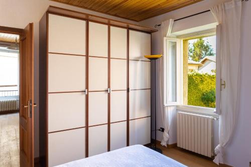 1 dormitorio con armario blanco grande y ventana en Magico Loft nel Centro Storico, en Toscolano Maderno