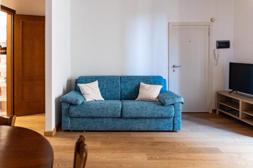 a blue couch in a living room with a television at Magico Loft nel Centro Storico in Toscolano Maderno