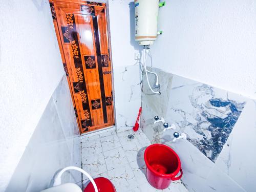 a bathroom with a tub and a red bucket at Sahara Family Homestay in Mysore