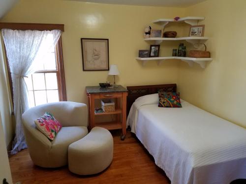 a bedroom with a bed and a chair next to a window at 1936 Art & International Home in Lancaster