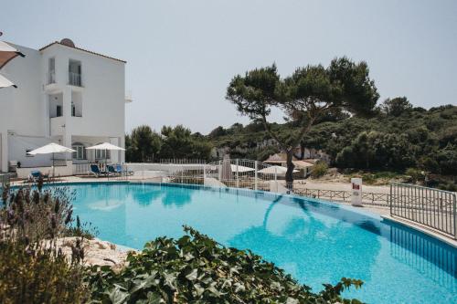 una gran piscina azul junto a un edificio blanco en HOSTAL XUROY en Sant Lluis