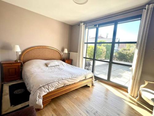 a bedroom with a bed and a large window at Oasis urbaine à LYON - jardin& jacuzzi in Lyon