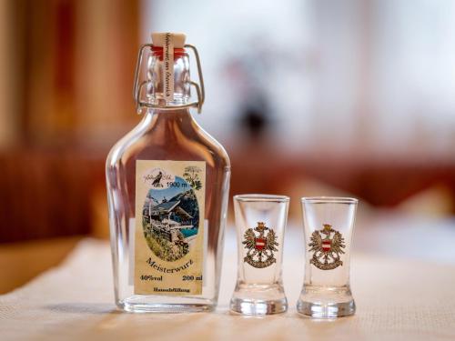 a bottle of honey and two glasses on a table at S'Dörfl Chalets in Mayrhofen