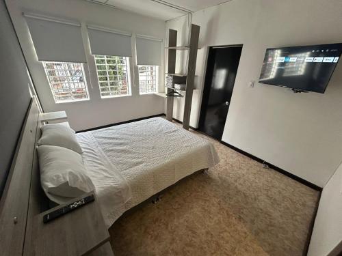 Schlafzimmer mit einem Bett und einem Flachbild-TV in der Unterkunft Hostel Quinta Camacho in Bogotá