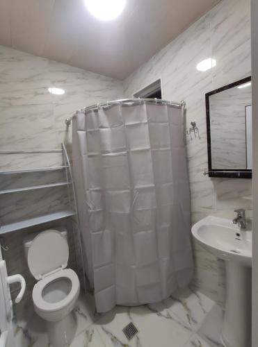 a white bathroom with a toilet and a sink at gabro in Mtskheta