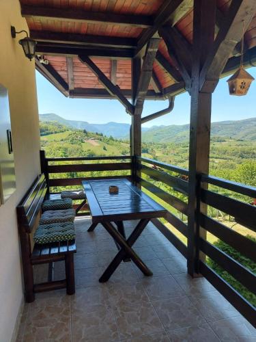 a table and a bench on a balcony with a view at Kuca za odmor Drina & Tara in Bajina Bašta