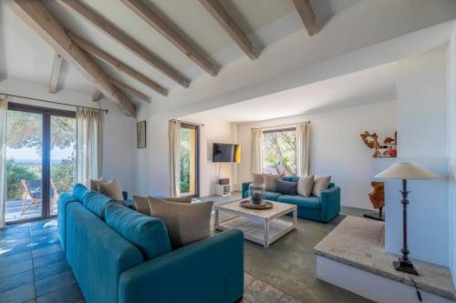 un soggiorno con divani blu e un tavolo di Villa Sud Corse 6ch piscine 27m, accès mer a Pianottoli-Caldarello