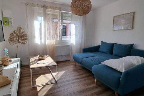 un salon avec un canapé bleu et une table dans l'établissement *Le Duplex de Ronsard*Plage et Centre-Ville, à Dunkerque