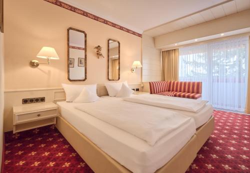 ヴュルツブルクにあるHotel Wittelsbacher Höhの白い大型ベッドと椅子が備わるホテルルームです。
