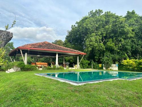 una piscina en un patio con un pabellón en Magalle Wewa Villa en Nikaweratiya