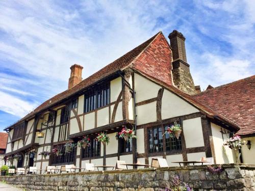 un edificio antiguo con flores en las ventanas en The Crown Inn, en Chiddingfold