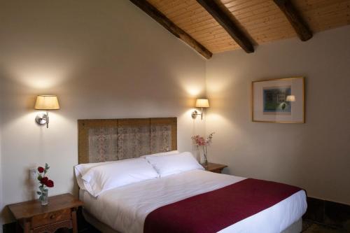 a bedroom with a large bed with two tables and two lamps at Hotel Pazo de Bieite in Boimorto